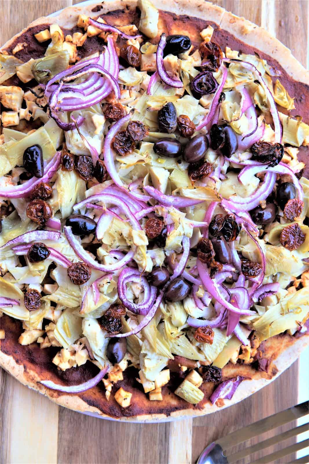 Grafted Pro pizza featuring artichokes, Kalamata olives, roasted garlic, caramelized onions, and Mediterranean toppings on a crispy crust for a gourmet vegan-friendly meal.